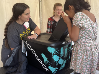 Microbiology Ph.D. student Iris Irby shows attendees glowing bacteria at an Exploration Expo booth hosted by the Center for Microbial Dynamics and Infection. (Photo Jess Hunt-Ralston)